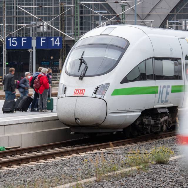 Menschen steigen mit Koffern in einen ICE-Zug der Deutschen Bahn ein.