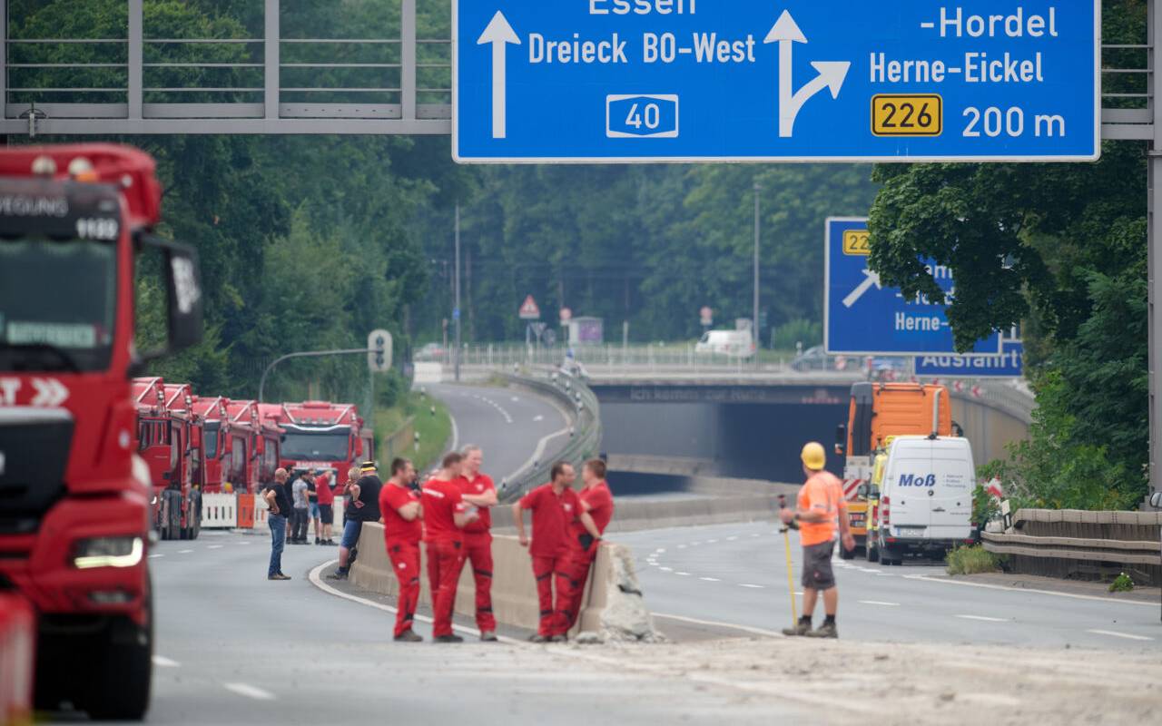 Arbeiter stehen auf der gesperrten A40-Autobahn im Ruhrgebiet.