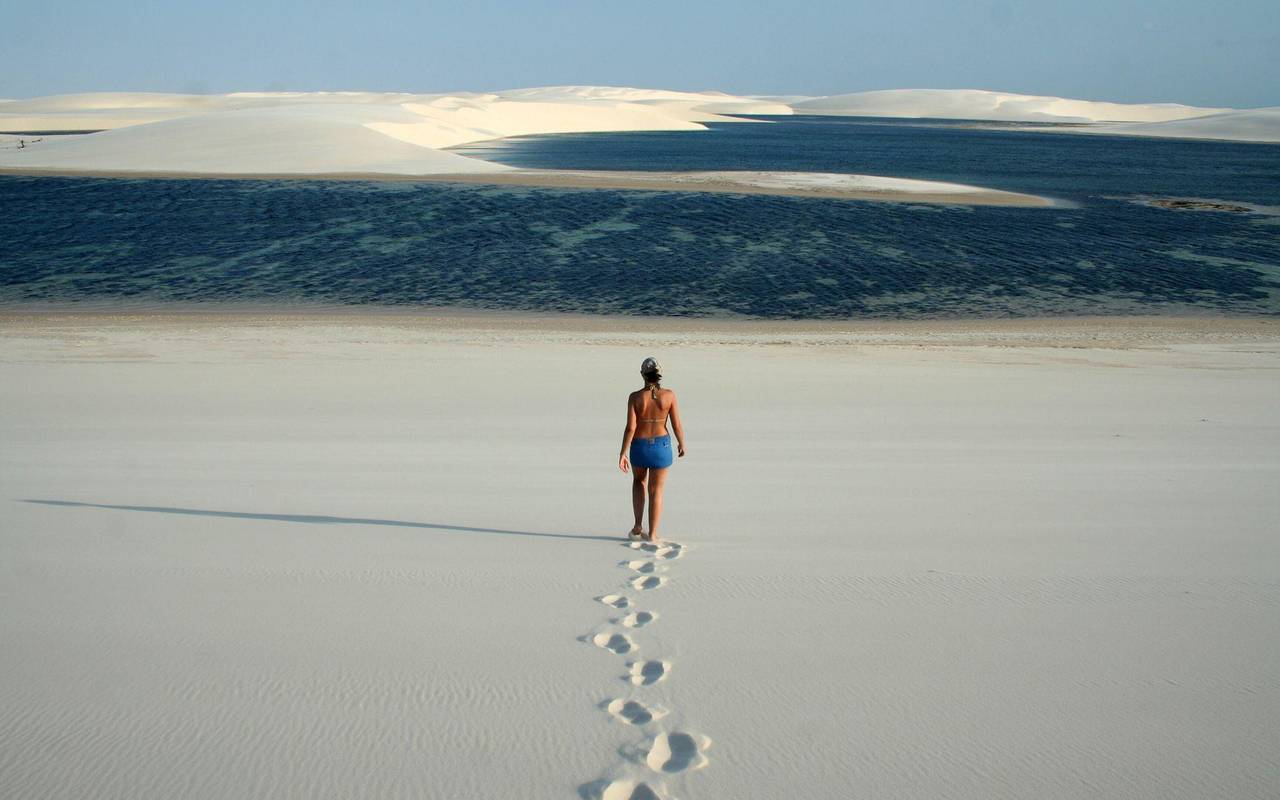 Frau läuft durch Dünenlandschaft zu einer kleinen Lagune