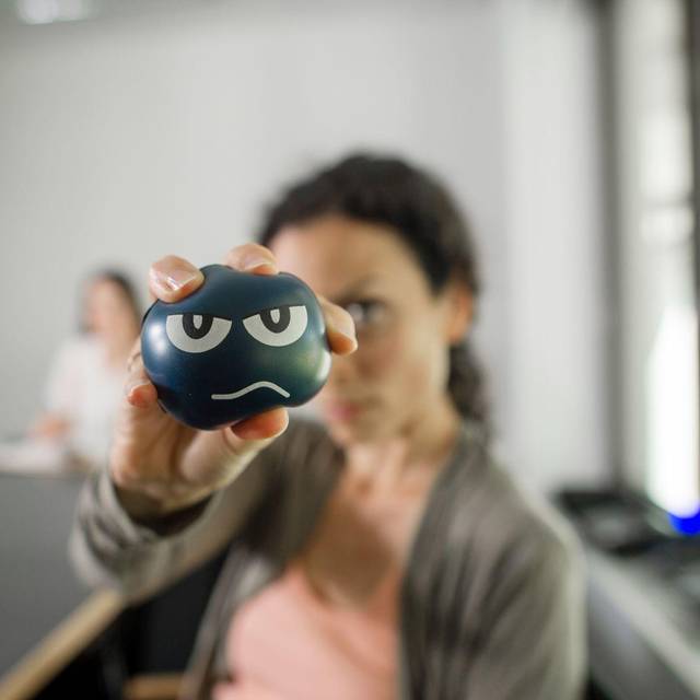 Eine Frau nutzt im Büro einen Anti-Aggressionsball