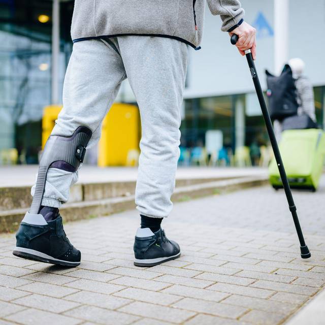 Ein Mann läuft mit einer Gehhilfe auf der Straße