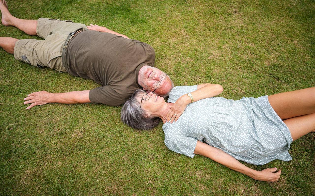 Ein älteres Paerchen liegt in einem Garten