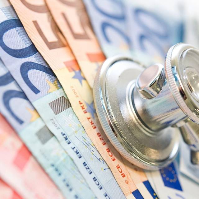Ein Stethoskop liegt auf Geldscheinen
