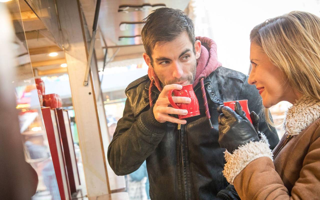 Ein Mann und eine Frau trinken Heißgetränk auf Weihnachtsmarkt