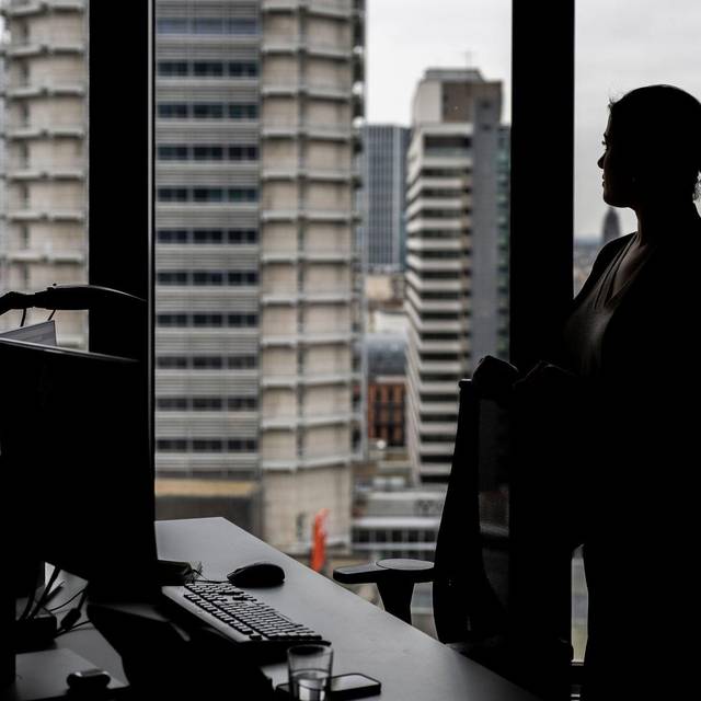 Frau steht an ihrem Arbeitsplatz am Fenster