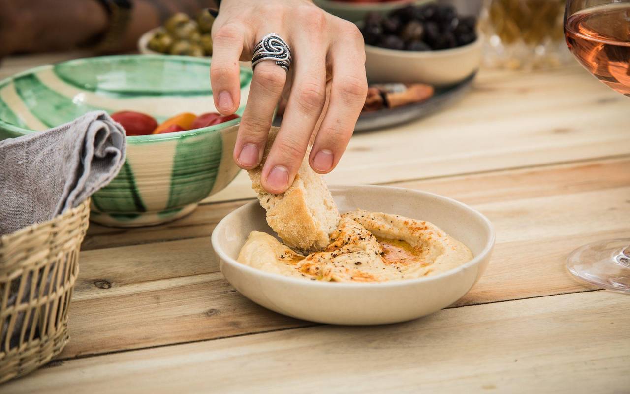 Ein Mann dippt ein Stück Brot in Hummus