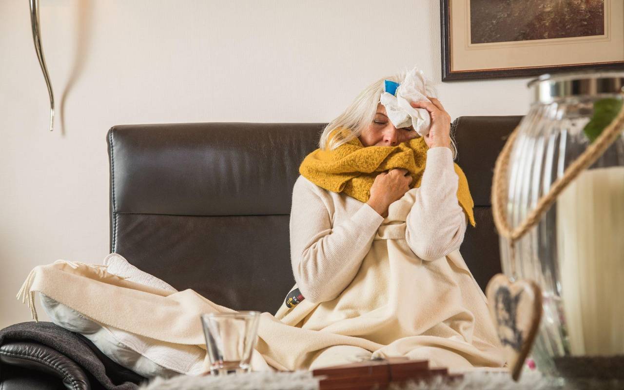 Eine Frau mit einer Erkältung auf einem Sofa