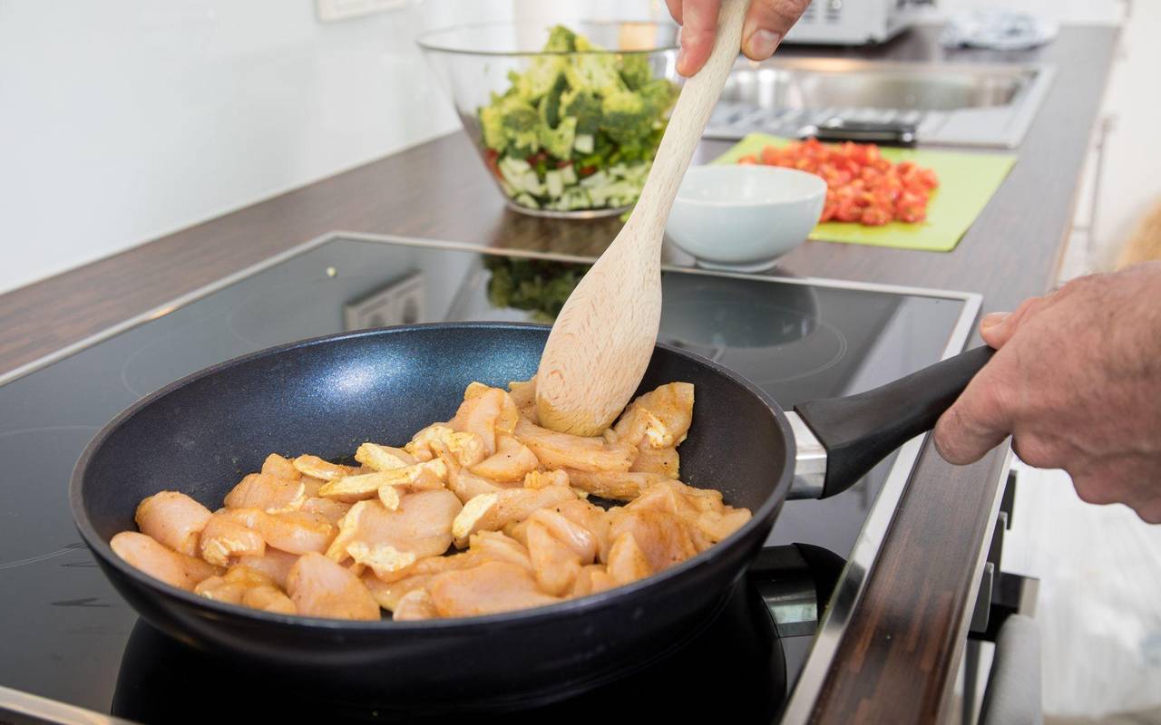 Ein Mann brät Hähnchenfleisch in einer Pfanne