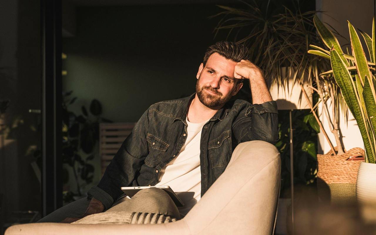 Mann sitzt gedankenvoll auf einer Couch