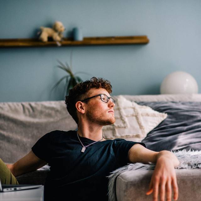 Ein junger Mann sitzt auf dem Boden vor seinem Computer