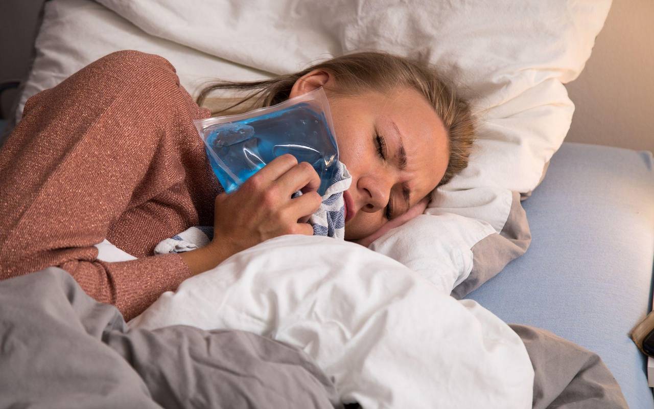 Eine Frau liegt mit Zahnschmerzen im Bett