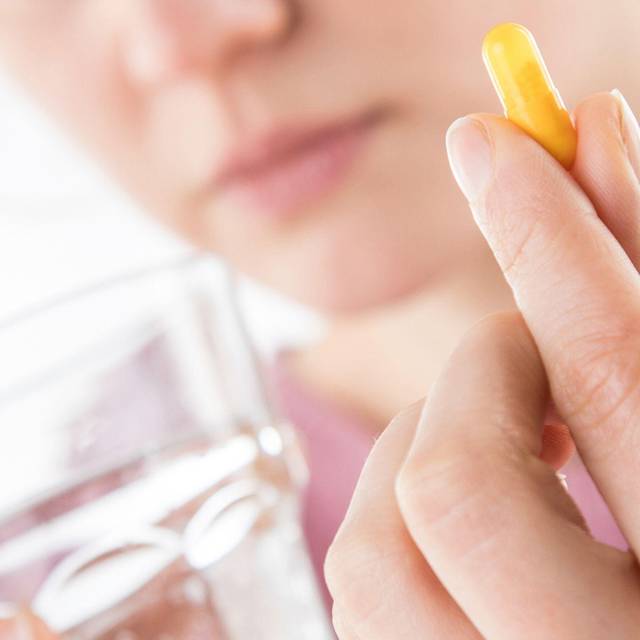 Frau hält eine Tablette in der Hand