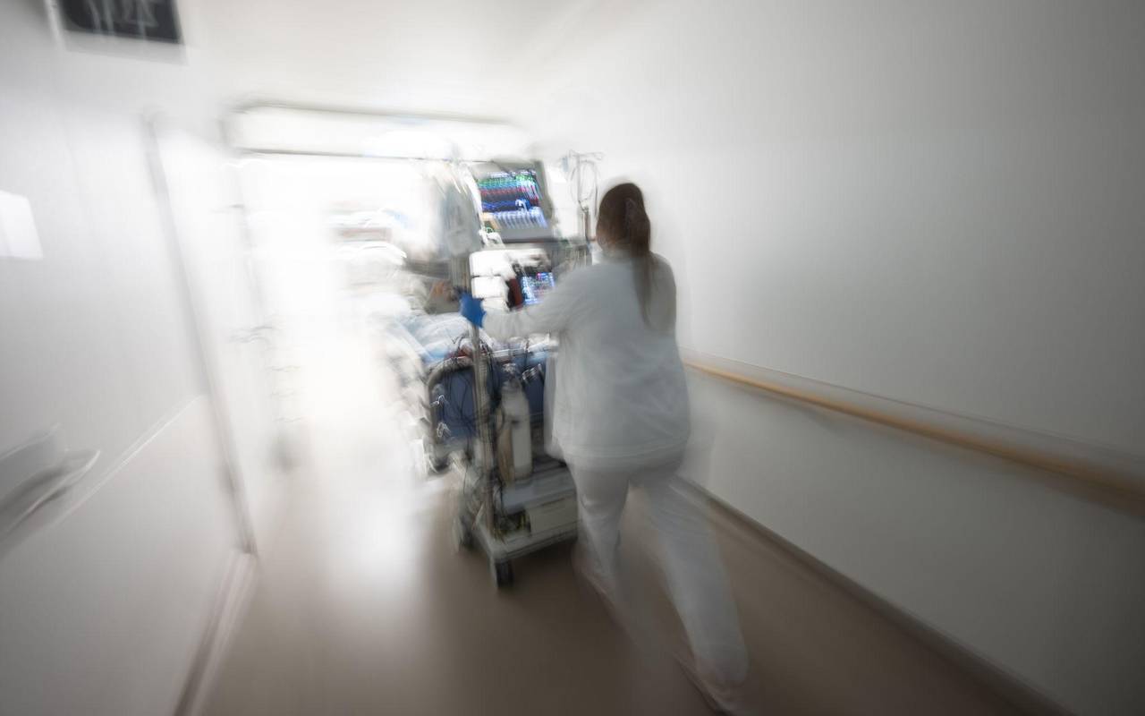 Pflegerin fährt eine Intensivpatientin durch denGang einer Klinik