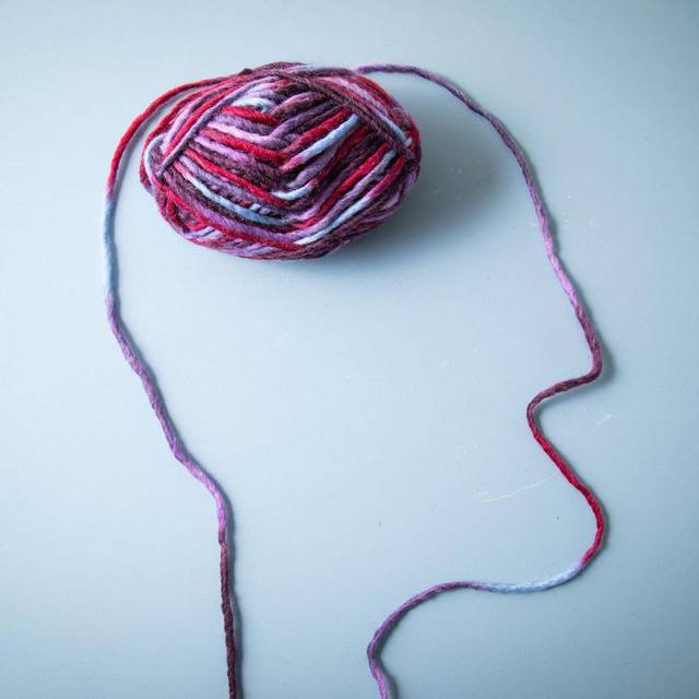 Die Silhouette eines Menschen und dessen Gehirn aus Garn