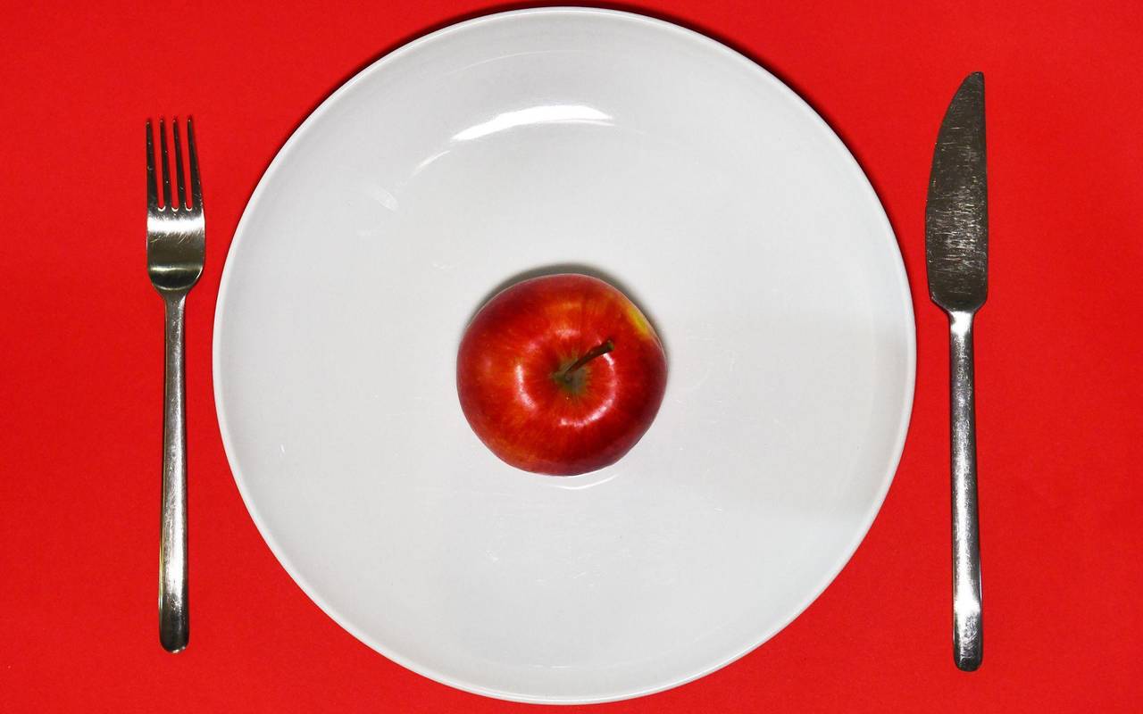 Ein Apfel liegt zum Verzehr bereit auf einem Teller