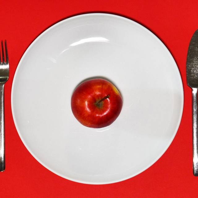 Ein Apfel liegt zum Verzehr bereit auf einem Teller