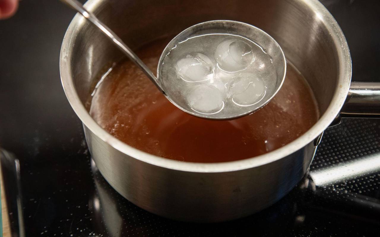 Eis schmilzt in einer Suppenkelle über einer Brühe