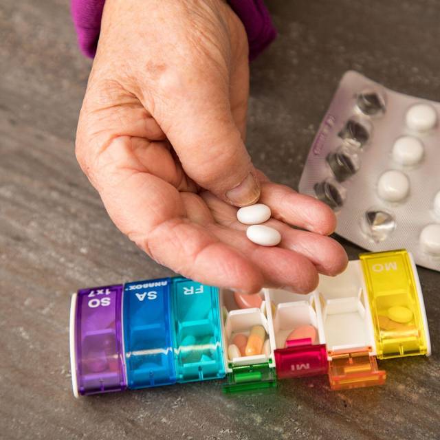Seniorin nimmt Tabletten aus einer Pillendose