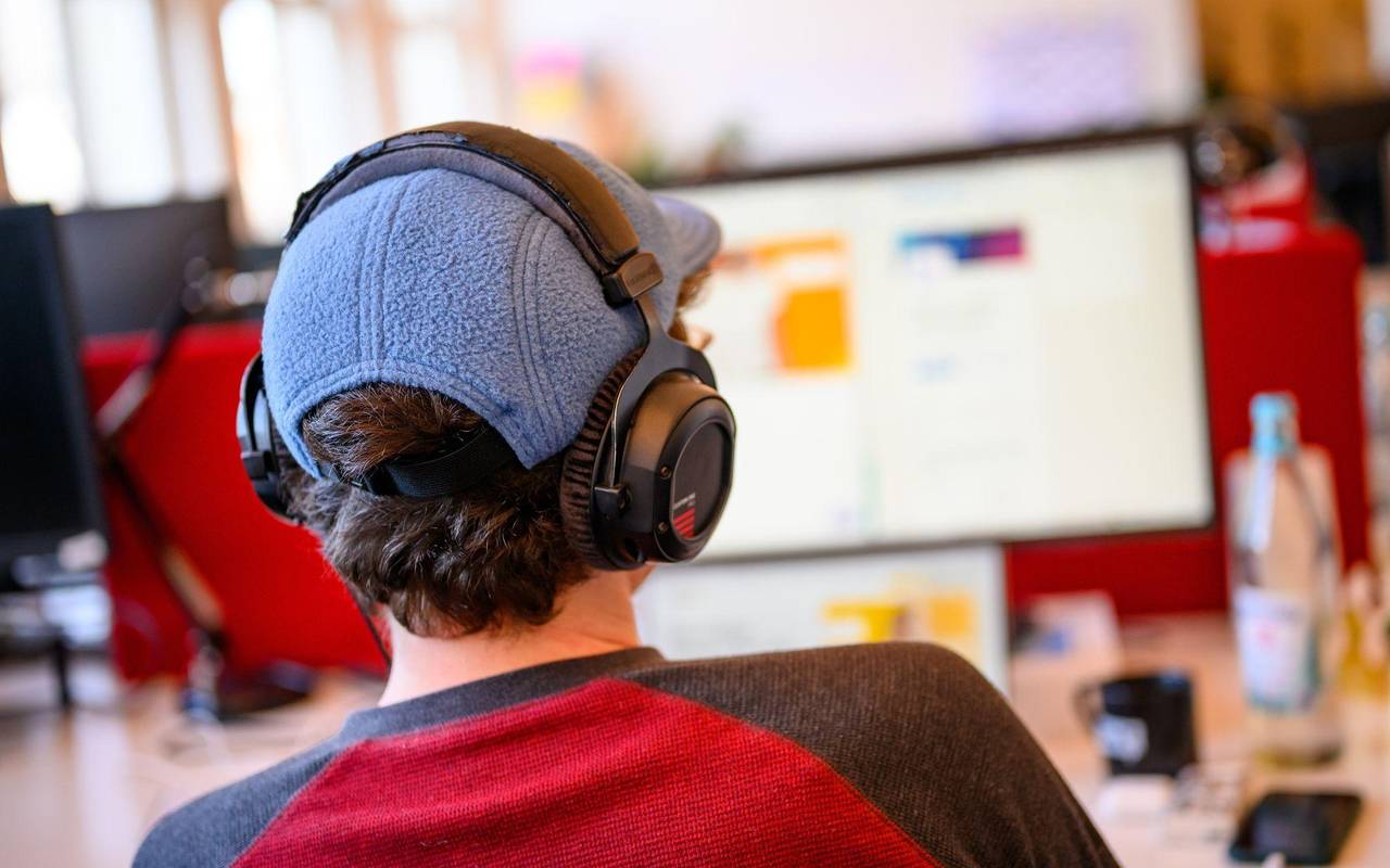 Ein Mitarbeiter mit Kopfhörern vor einem Computer-Bildschirm