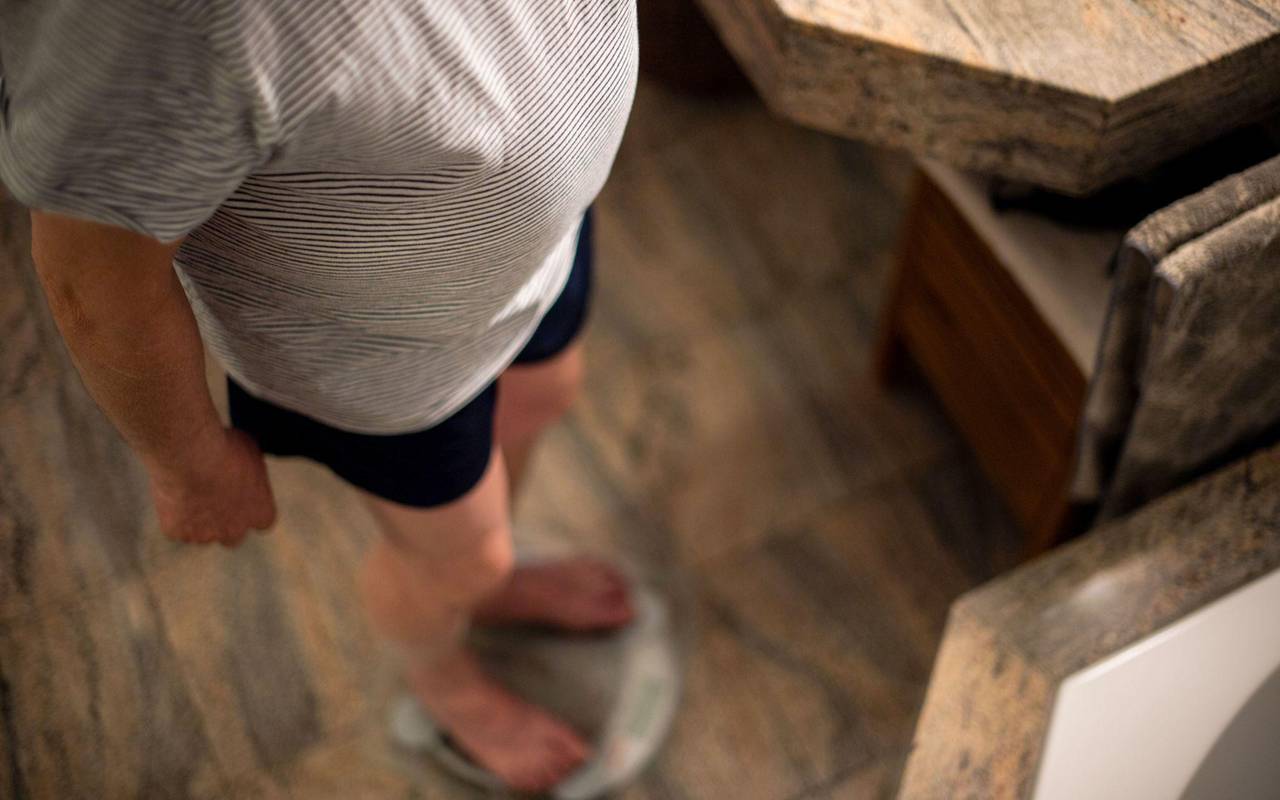 Ein Mann steht im Pyjama auf der Waage
