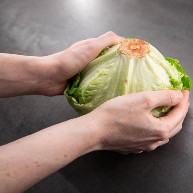 Frau hält einen Salatkopf in den Händen