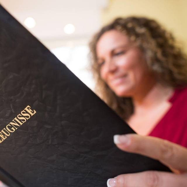 Frau liest in einer Mappe mit der Aufschrift «Zeugnisse»