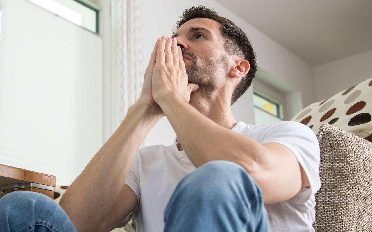 Mann sitzt nachdenklich im Wohnzimmer