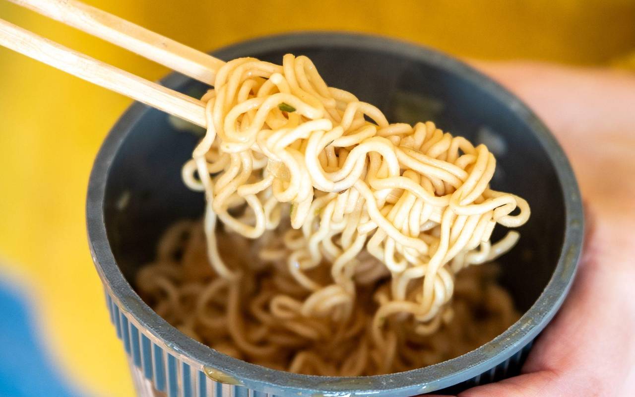 Eine Frau hält einen Becher Instantnudeln in der Hand