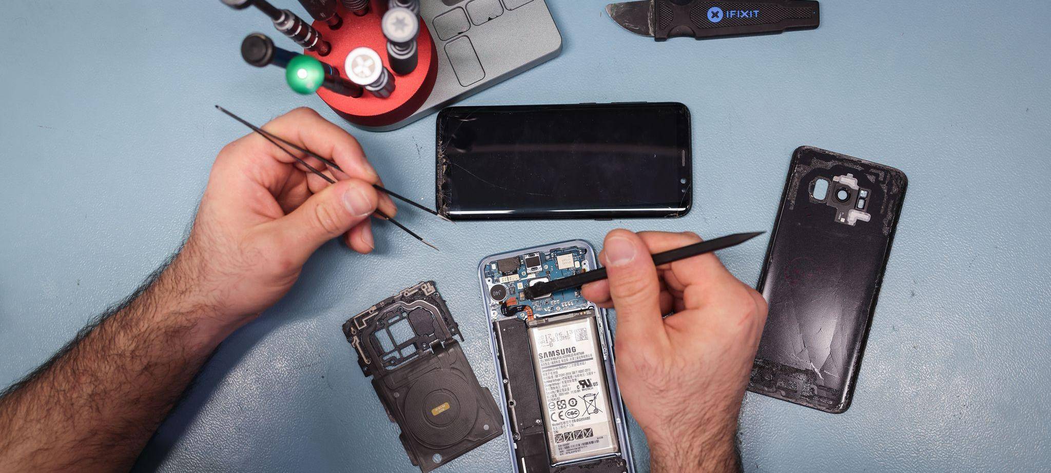 Techniker arbeitet an einem Smartphone mit defektem Display