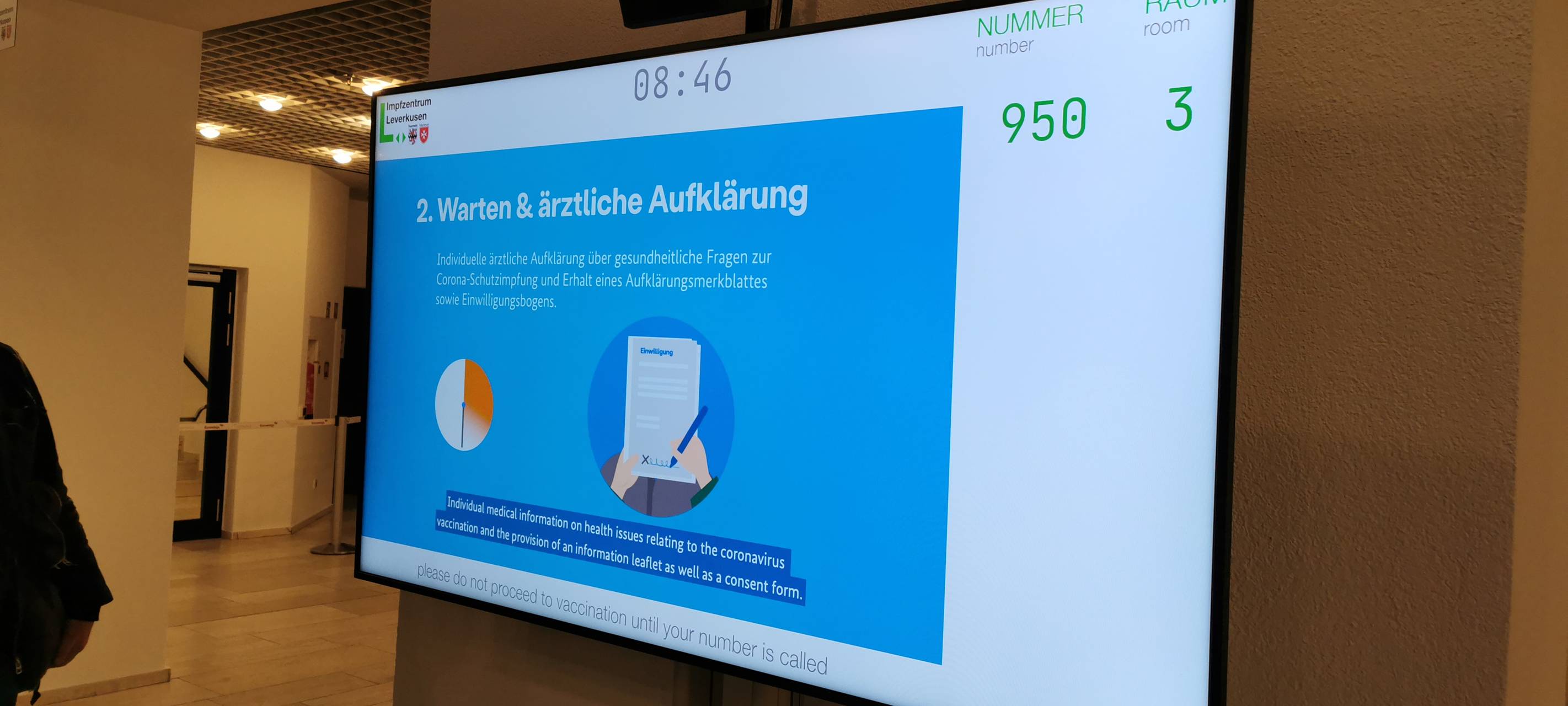 Zum Impfraum geht ihr erst, wenn auf dem Display die Nummer auf eurem Armband angezeigt wird.
