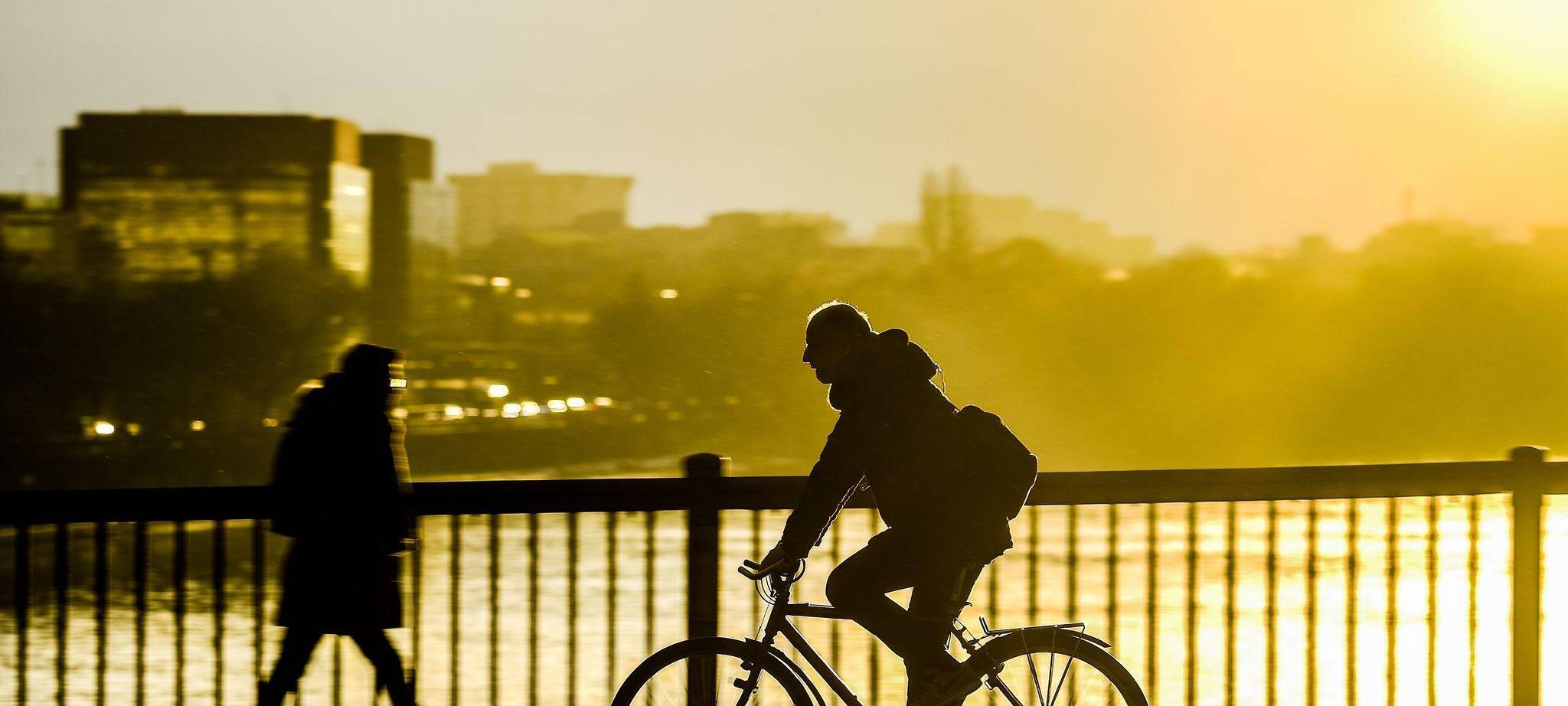 Fahrradfahrer fährt im Sonnenuntergang über eine Brücke