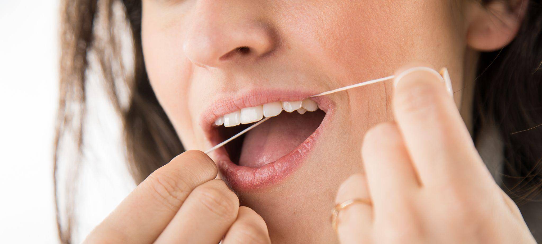 Eine Frau benutzt Zahnseide