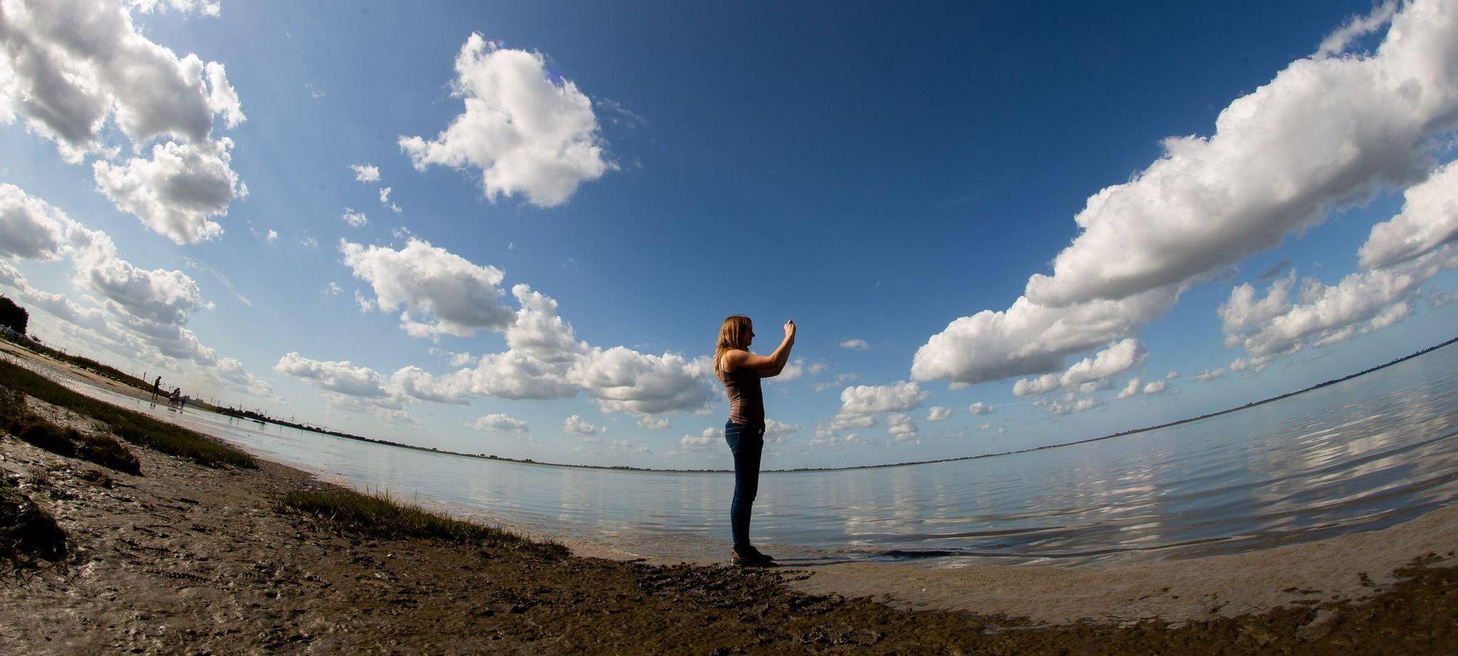 Frau fotografiert mit einem Smartphone die Landschaft