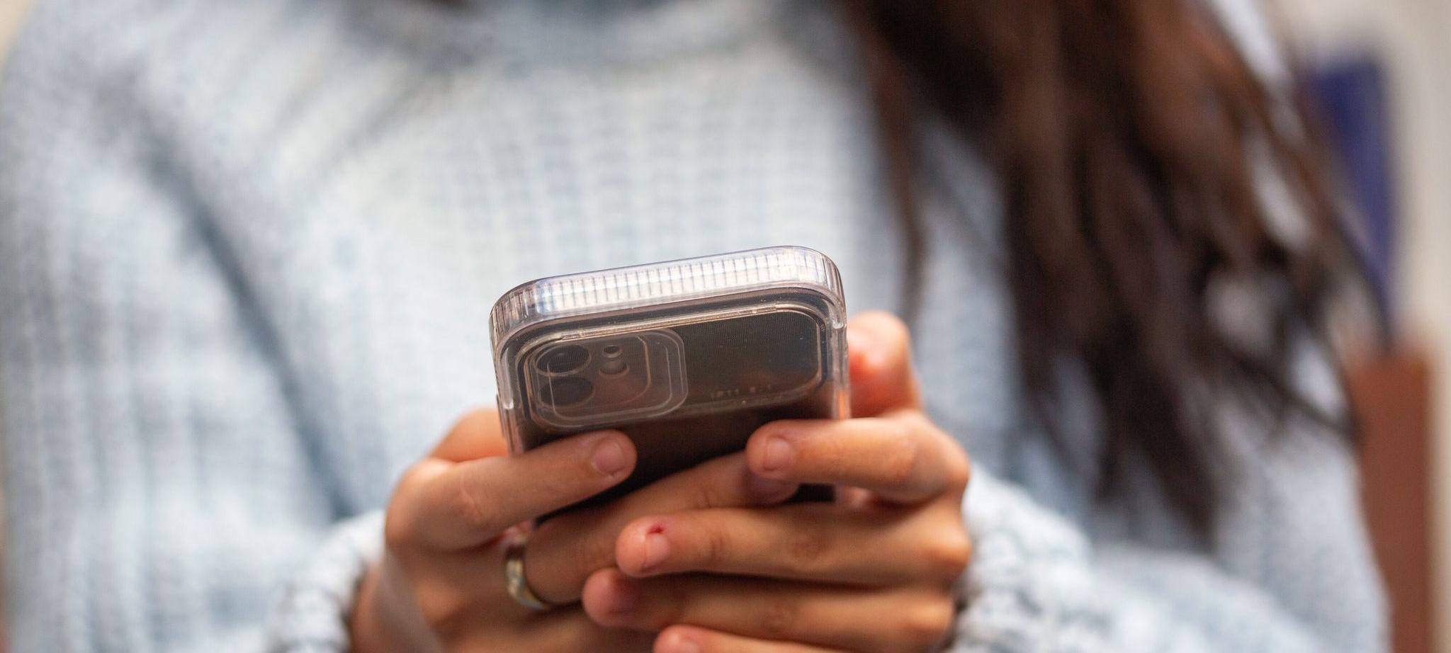 Eine junge Frau hält ein Smartphone in den Händen