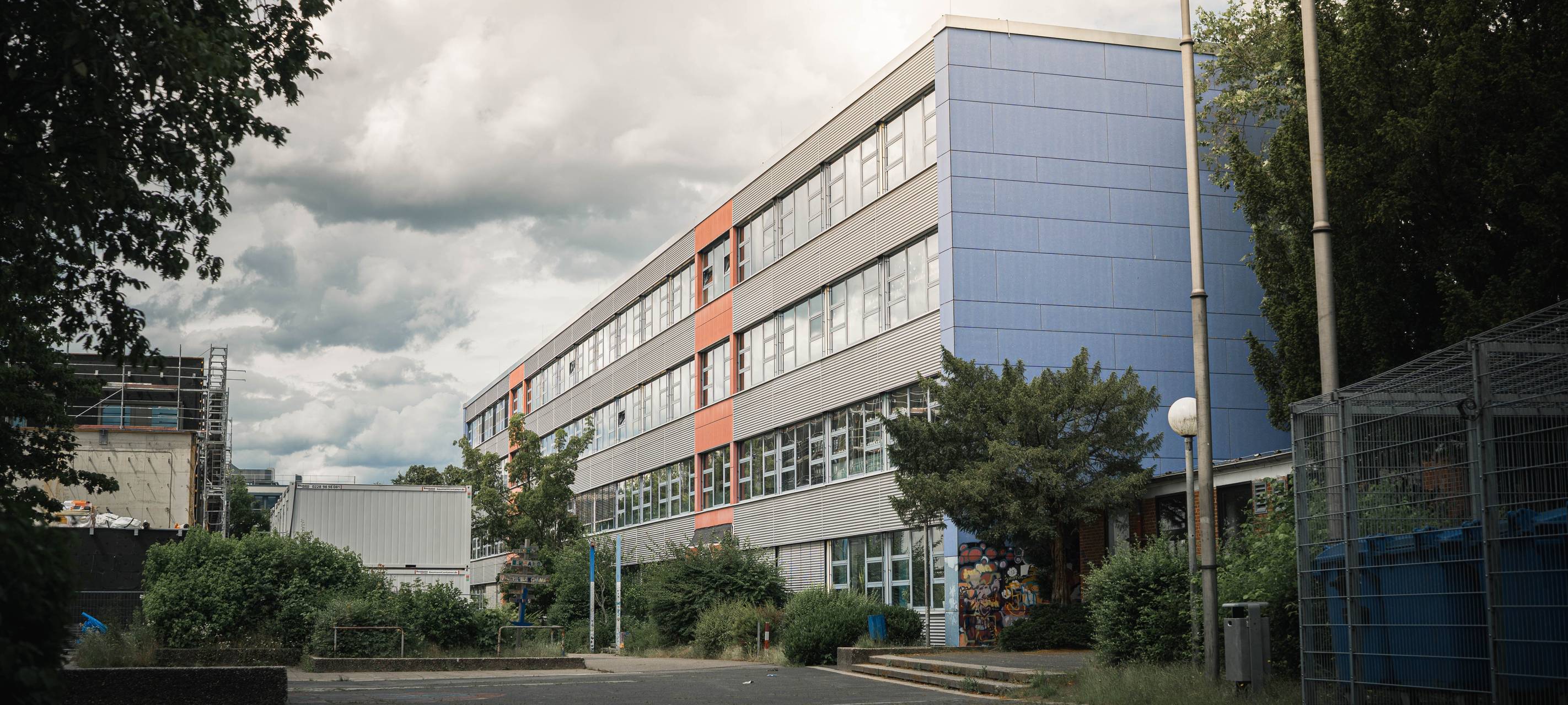 Gebäude der Theodor-Wuppermann-Schule mit blau-grauer Fassade und Bäumen am Rand des Schulgeländes.