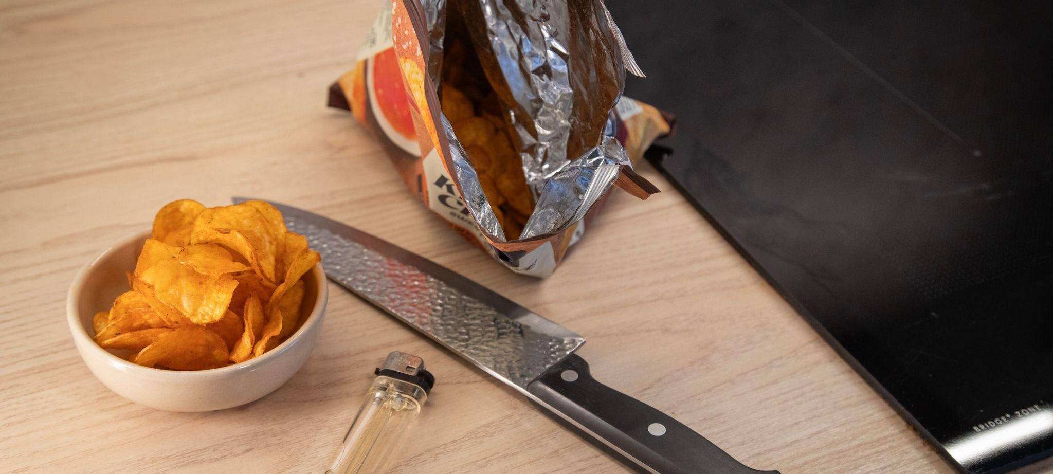 Chipstüte liegt neben einem Messer und einem Feuerzeug