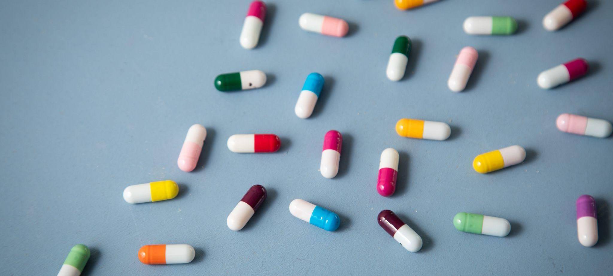 Unterschiedlich farbige Tabletten liegen auf einem Tisch