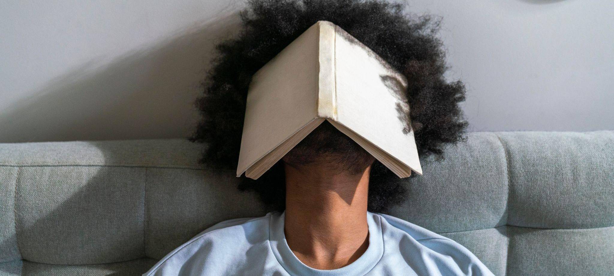 Ein Mann verdeckt sein Gesicht mit einem Buch