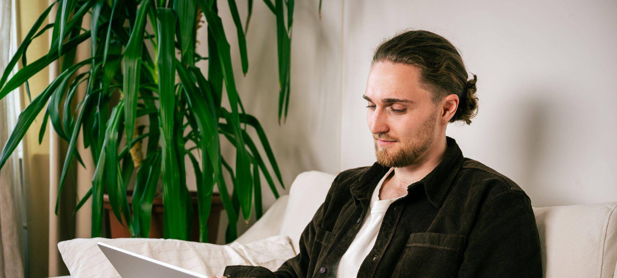 Ein junger Mann nutzt einen Laptop auf dem Sofa