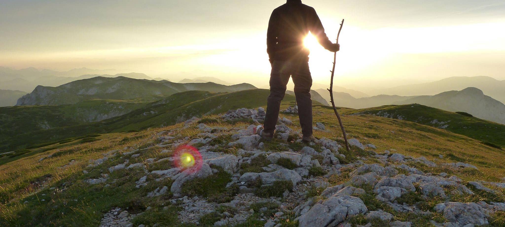 Wanderer genießt bei Sonnenuntergang die Aussicht über die Berge