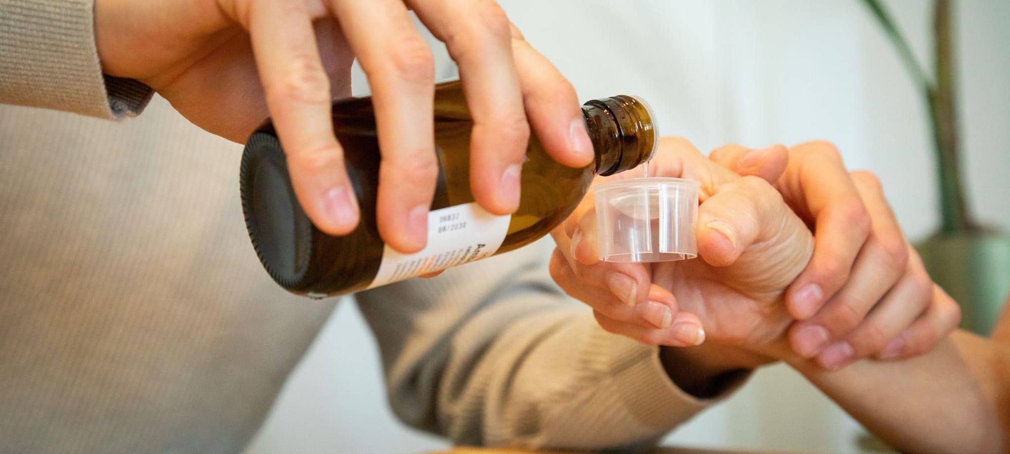 Ein junger Mann hilft einer Frau beim Medikament einnehmen